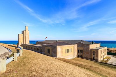 Buildings by sea against blue sky