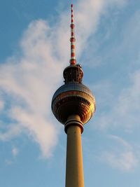 Low angle view of communications tower against cloudy sky