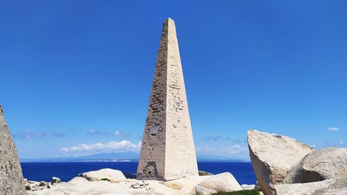 Low angle view of rocks against clear blue sky