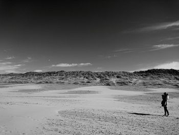 Man walking on sand at beach against sky