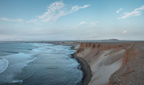 Panoramic view of sea next to cliff against sky