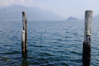 Wooden posts in lake against sky