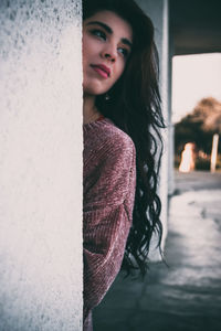 Portrait of smiling woman standing against wall