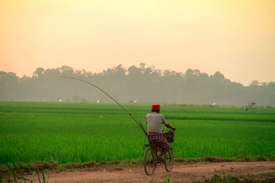 Woman with umbrella on field against sky