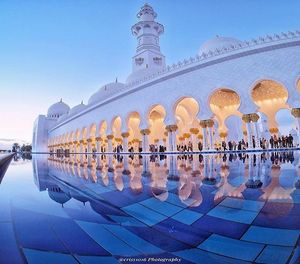 Reflection of building on tiled floor against blue sky