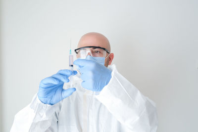 Young cautious doctor in mask holding syringe. covid-19 vaccination.