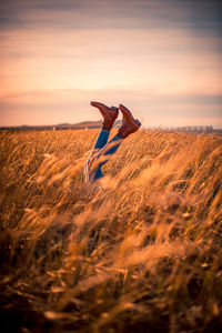 Man jumping on field against sky during sunset