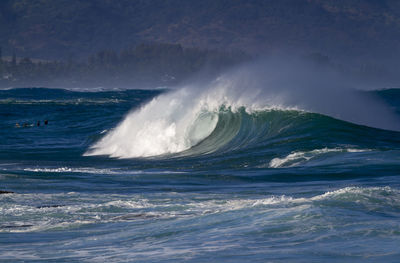 Waves splashing in sea against sky