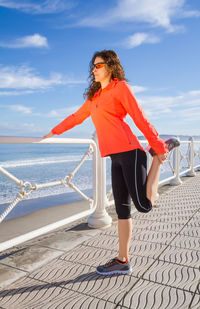 Woman standing by railing against sea