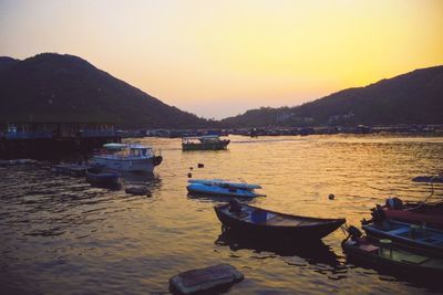 Boats in sea at sunset