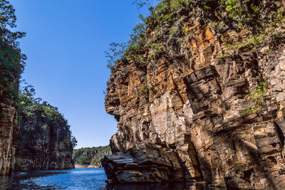 Rock formations in sea against clear sky