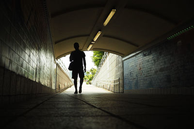 Silhouette man walking in tunnel