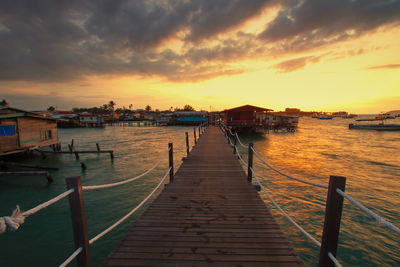 Pier over sea against sky during sunset