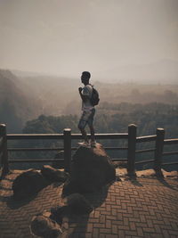 Man standing on railing against mountain