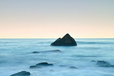 Scenic view of rocks in sea against clear sky