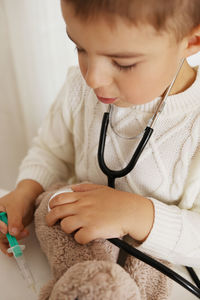 Cute little boy playing doctor at home and curing plush toy. sweet toddler child using stethoscope