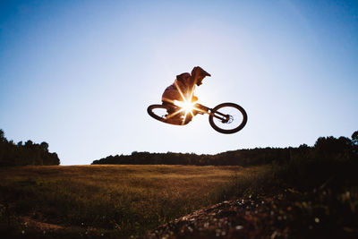 Man performing bicycle stunt against sky