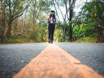 Full length of woman walking on road in forest