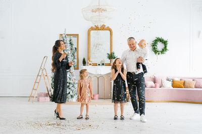 Family with young children playing with confetti at a new year celebration, a homely atmosphere