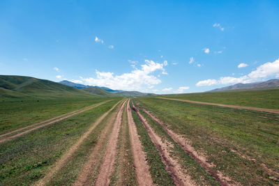 Panoramic view of road amidst field against sky