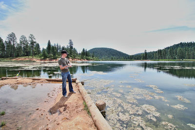 Man standing by lake against sky