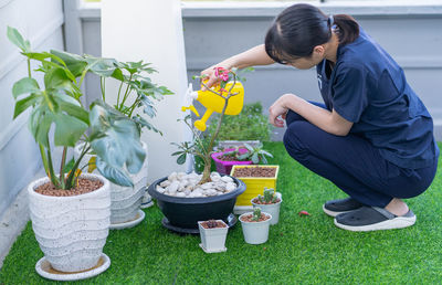 Woman standing by potted plants in yard
