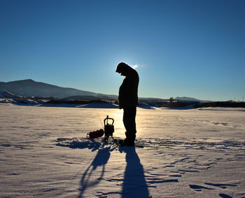 Silhouette man standing on beach against clear sky