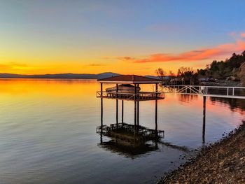 Pier over lake against sky during sunset