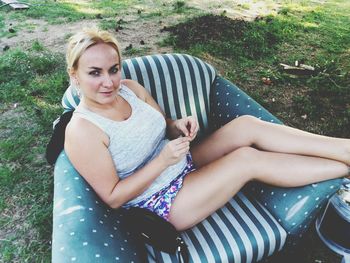 High angle portrait of woman relaxing on chair at yard