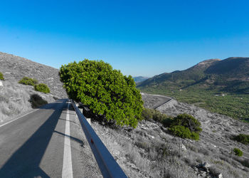 Road by mountain against clear blue sky