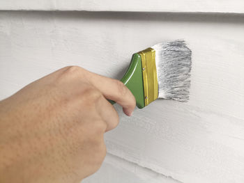 Hand holding brush painting wall