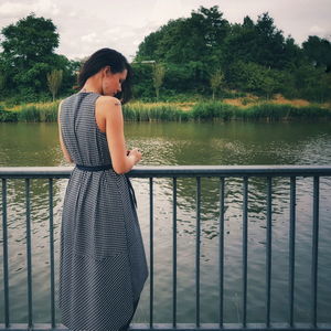 Woman standing by railing against lake