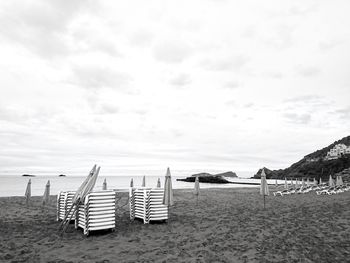 Chairs on beach against sky