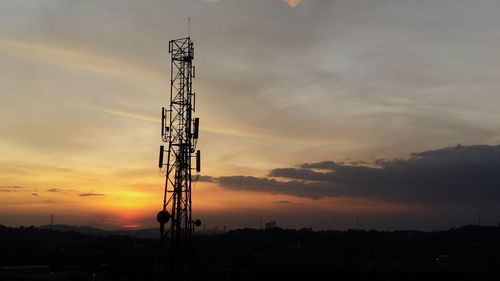 Silhouette of communications tower against sky during sunset