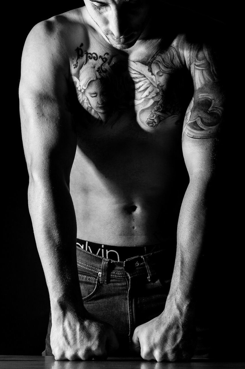 shirtless, one person, tattoo, real people, lifestyles, indoors, young adult, black background, men, muscular build, abdomen, human hand, day, people