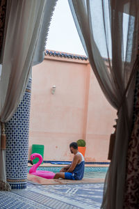 Rear view of woman sitting on curtain