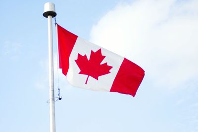 Low angle view of canadian flag against cloudy sky