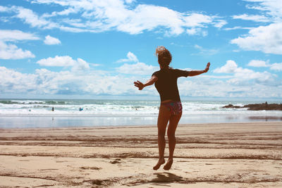 Rear view of woman jumping at beach