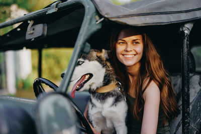 Portrait of young woman with dog in car