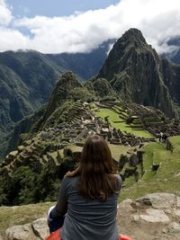 Rear view of woman looking at mountains against sky