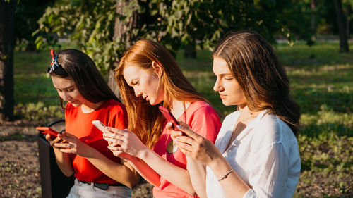 Diverse three girl friends using their phones outdoors. group gen z young people using mobile