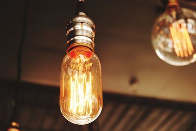 Low angle view of illuminated light bulbs hanging from ceiling