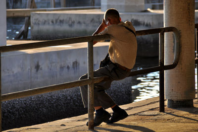 Man sitting on railing by canal