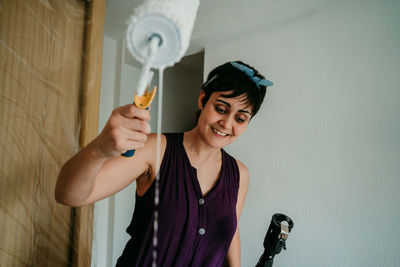 Portrait of a smiling young woman standing against wall