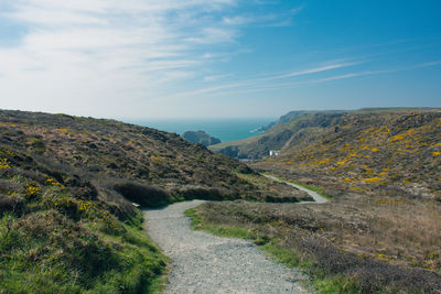 Empty footpath amidst mountains against blue sky