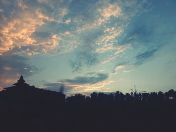 Silhouette trees and buildings against sky at sunset