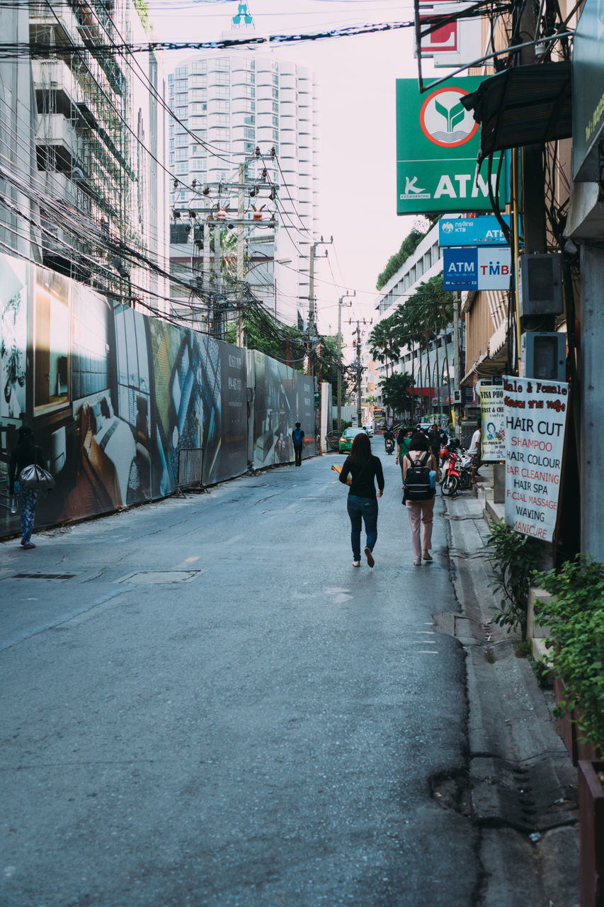 PEOPLE WALKING ON STREET AMIDST BUILDINGS IN CITY