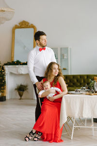 Stylish parents with a baby in the christmas living room. mom sits 