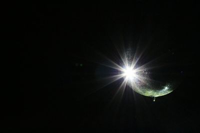 Low angle view of illuminated lighting equipment against black background