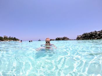 Portrait of man swimming in sea against clear blue sky